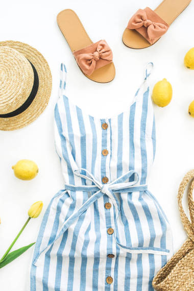 夏季女性時(shí)尚的構(gòu)圖。禮服, 拖鞋, 稻草, 檸檬, 郁金香花和配件在白色的背景。平躺, 頂部視圖