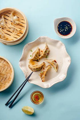 饺子饺子, 鸭煮在竹蒸笼与酱油和芝麻种子板上的蓝色背景下, 顶部视图