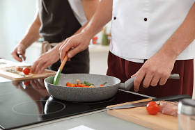男厨师在电炉上烹调蔬菜, 特写