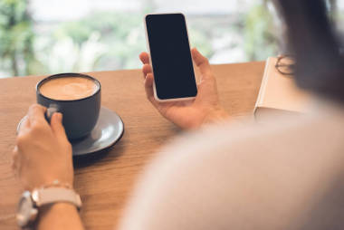 咖啡杯用智能手機(jī)在咖啡館里的女人的部分看法