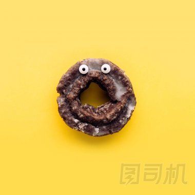 滑稽的沖擊面孔釉面巧克力蛋糕甜甜圈在柔和的黃色背景, 創(chuàng)造性的極小的萬圣節(jié)概念
