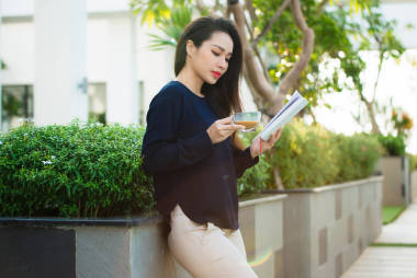 愉快的年轻妇女藏品书喜爱文学分析小说在阳光明媚的日子里在校园咖啡馆的阳台上休闲时间