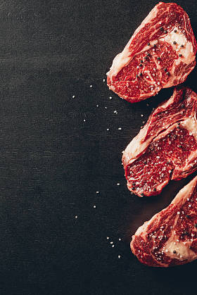 厨房表面生肉牛排和香料的顶部视图
