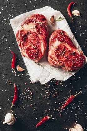 厨房餐桌上生牛排、烘纸、散香料的提升