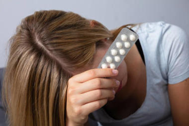 一個(gè)年輕的不開心的女人抓著藥的特寫