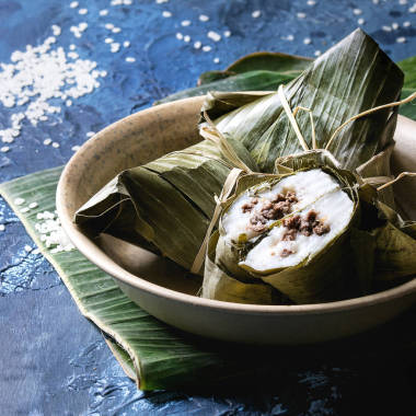 亞洲大米 piramidal 由大米木薯粉制成的饅頭, 在香蕉葉上 bowlwith, 上面有藍(lán)色的紋理背景。關(guān)閉, 空間。方形圖像