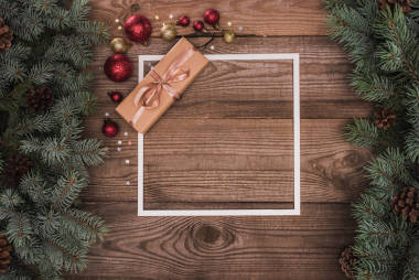 白色框架的頂部看法, 圣誕節(jié)禮物和閃亮的華而不實在木表面用冷杉小枝和松樹錐體