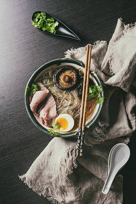传统的日本面条汤, 蘑菇, 鸡蛋, 切片牛肉和蔬菜, 在陶瓷碗中供应木筷和白色勺子, 在黑暗的背景布。平躺, 空间