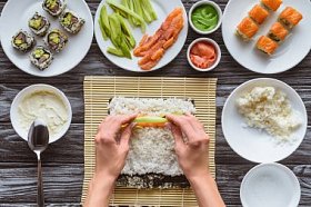 裁切拍摄的人烹饪美味的寿司卷与鲑鱼, 鳄梨和黄瓜