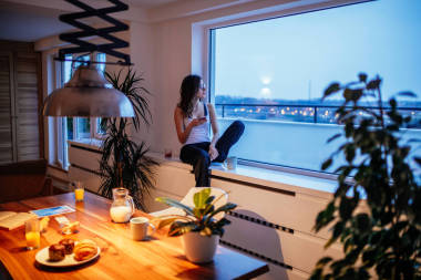 窗口和发短信在家里一个人坐在一个年轻女人的照片