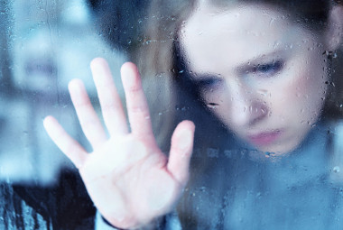 憂郁和悲傷的女孩在雨中的窗口