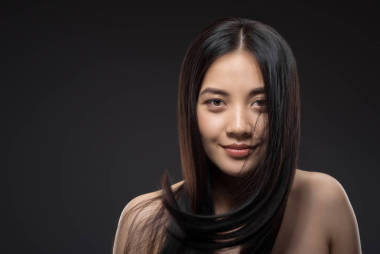 年輕的微笑亞洲婦女的肖像美麗和健康的黑發(fā)看著相機孤立黑色