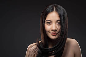 年轻的微笑亚洲妇女的肖像美丽和健康的黑发看着相机孤立黑色