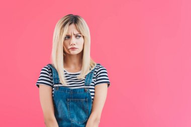 担心美丽的女孩牛仔整体看着远离粉红色的孤立
