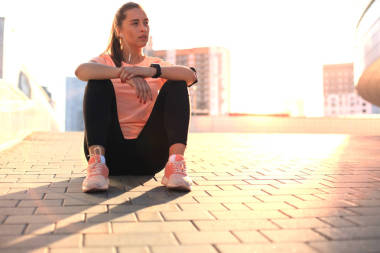 年轻迷人的运动女孩在街上休息手机和音乐, 户外日落或日出在城