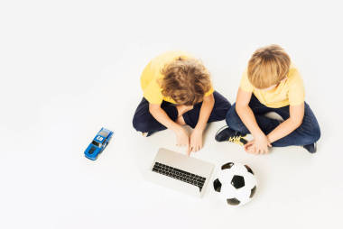 兩個(gè)小男孩使用筆記本電腦, 而坐在白色的玩具隔離的頭頂視圖