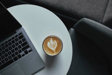 咖啡桌上的咖啡杯和笔记本电脑的顶部视图