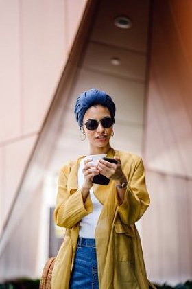 年轻和有吸引力的马来穆斯林妇女在手中手持智能手机在白天