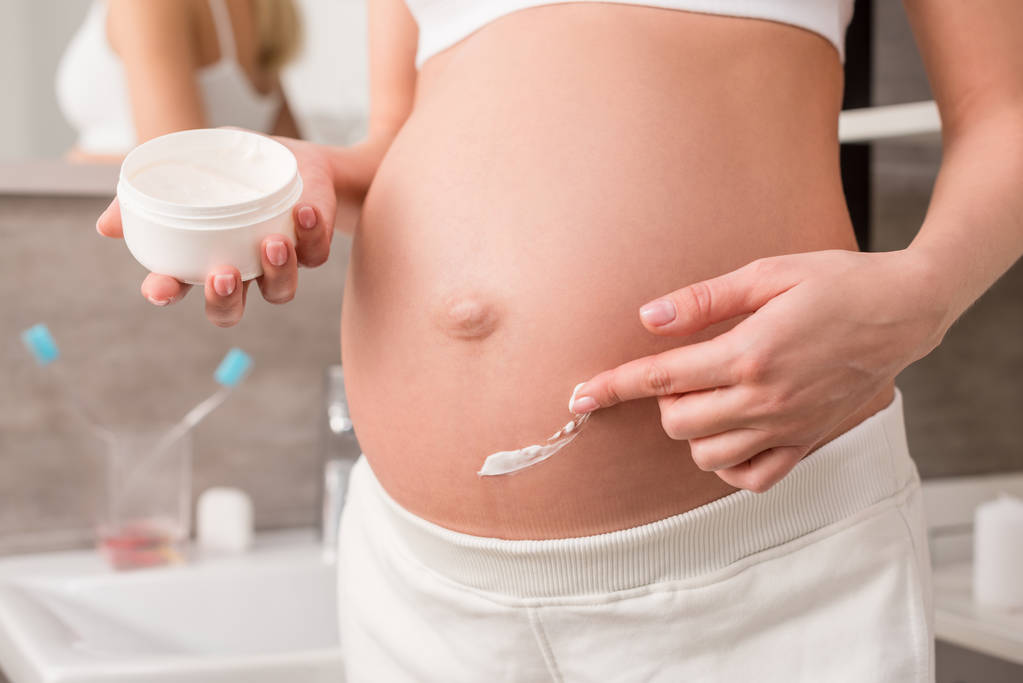 怀孕妇女的短款镜头涂抹奶油在腹部, 以避免妊娠纹在浴室 怀孕妇女的短款镜头涂抹奶油在腹部, 以避免妊娠纹在浴室