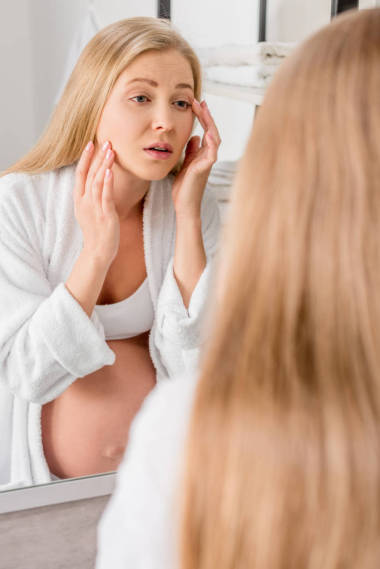 有皮膚問題的孕婦看著她的臉通過鏡子在浴室