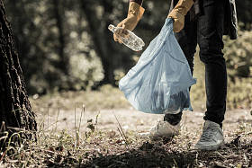 年轻的瞳孔穿牛仔裤和运动鞋收集空瓶子在森林