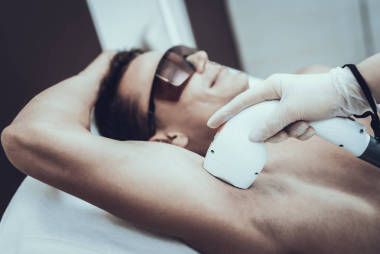 年轻男子在水疗沙龙激光脱毛。美容院的人现代美容。专业的美容师。医生与激光报告。男人的美容理念。眼镜里的人