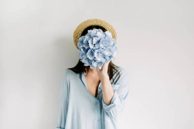 年輕女子舉行藍(lán)色繡球花花束在白色背景。平躺, 頂部視圖