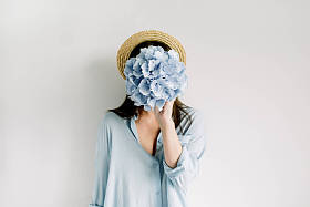 年轻女子举行蓝色绣球花花束在白色背景。平躺, 顶部视图