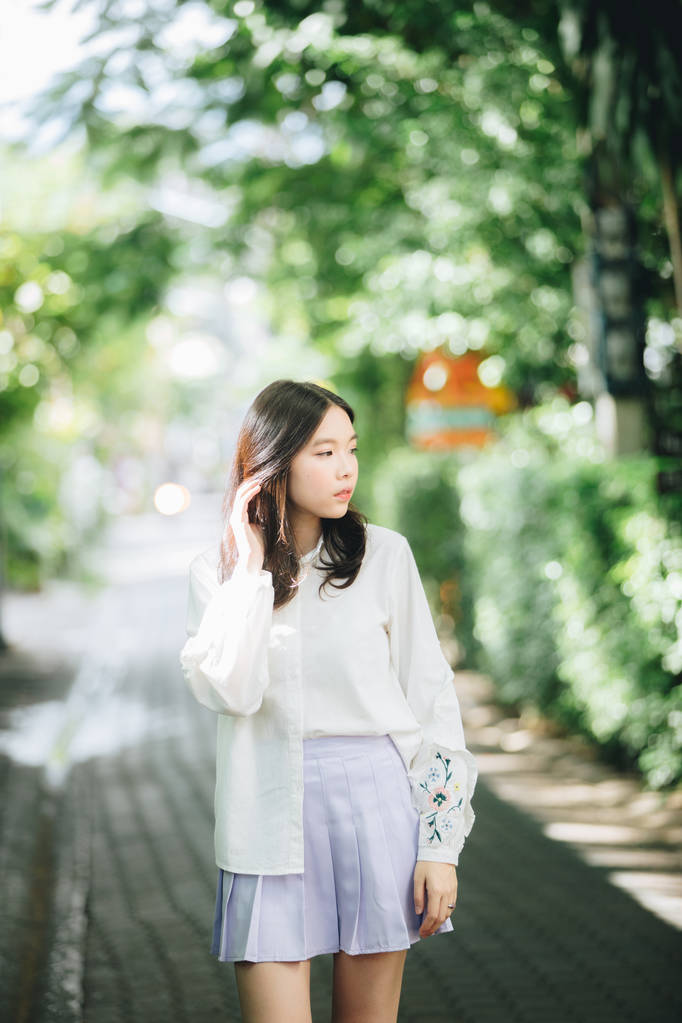 亚洲女孩的肖像，身穿白色衬衫和裙子，外型都市老式电影风