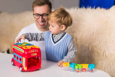 年輕快樂的父親帶著可愛的小兒子在室內(nèi)開發(fā)玩具