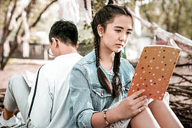 集中黑发女孩阅读浪漫故事在公园