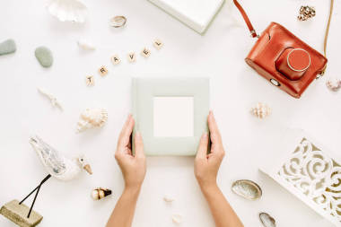 女士手拿著相冊。復古相機, 在白色背景的鳥雕塑。平躺, 頂部視圖旅行模型