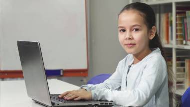 快樂美麗的亞洲小女孩使用筆記本電腦微笑