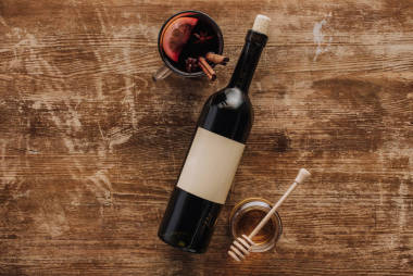 在杯子, 酒瓶和蜂蜜在木桌上的热葡萄酒的顶部视图