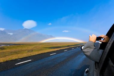 一輛車的人射冰島風(fēng)景與雙彩虹