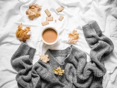 一杯咖啡, 灰暖針織毛衣超大, 黃色干葉子在床上-舒適的家庭靜物, 頂部視圖。復(fù)制空間