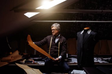 成熟的裁缝工作与切割模式在缝纫车间在傍 成熟的裁缝工作与切割模式在缝纫车间在傍