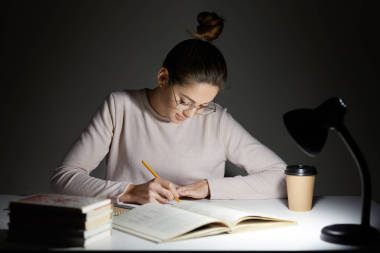 忙自由職業(yè)者重寫 infrormation 到記事本, 準(zhǔn)備文章出版, 讀書, 寫一些筆記在組織者, 飲料外賣咖啡, 坐在黑暗中, 穿著圓大眼鏡