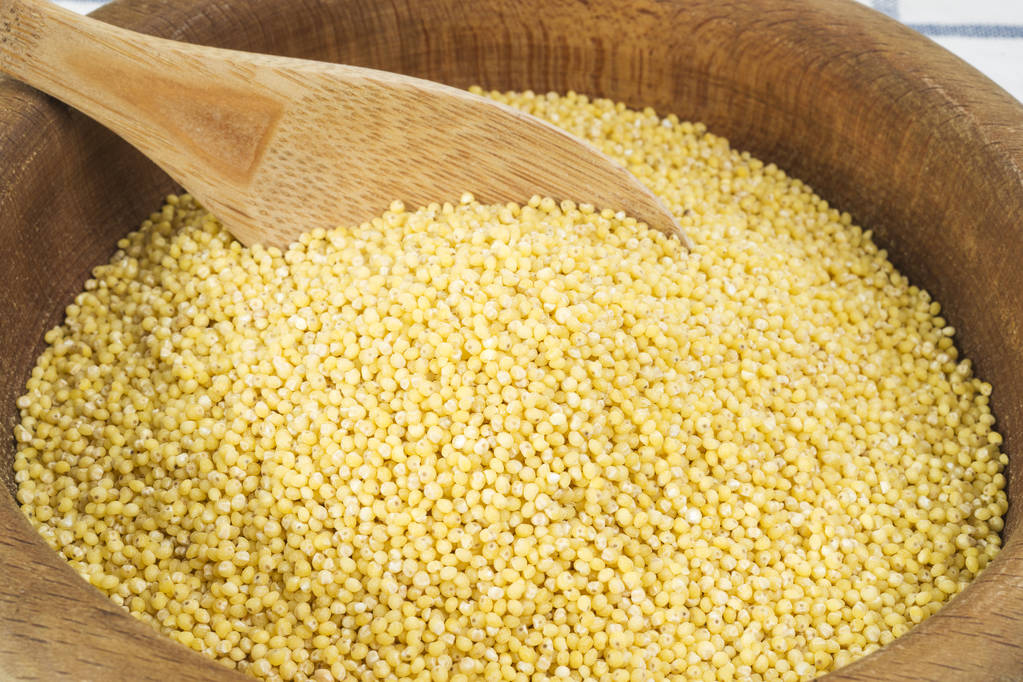 小米在一个木制的碗在背景上, 关闭 小米在一个木制的碗在背景上, 关闭