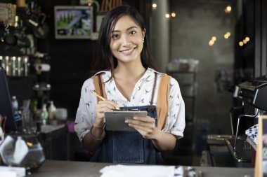 亞洲婦女咖啡師微笑和使用中咖啡的咖啡機計數(shù)器-店工作的女人小企業(yè)所有者食物和喝咖啡廳概念