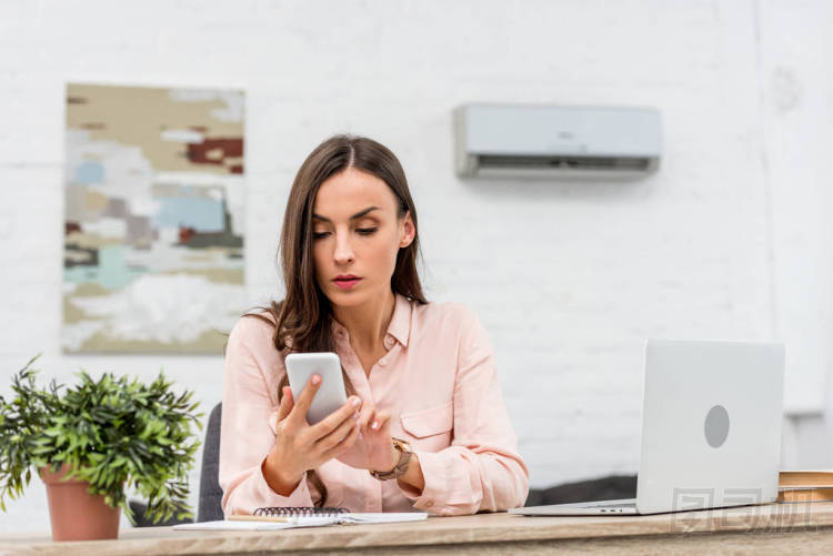 有吸引力的年輕女實(shí)業(yè)家在辦公室工作時使用智能手機(jī)