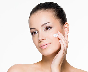 美丽的女人脸上应用奶油图片