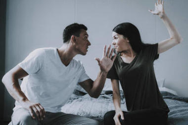 女人和男人在家里坐在床上打架。已婚夫婦坐在灰色格子和爭吵。憤怒的丈夫和妻子在臥室發(fā)生沖突。家庭關(guān)系問題概念