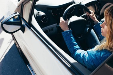 年輕婦女的側(cè)視圖與手在方向盤駕駛汽車