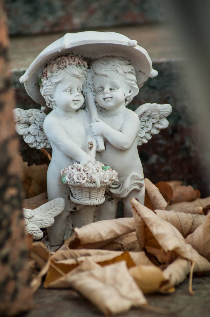 在墓地墓的两个石头天使与伞特写镜头 在墓地墓的两个石头天使与伞特写镜头