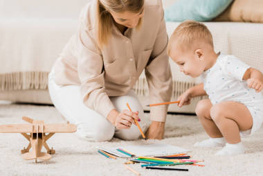 快樂的母親和可愛的幼兒在托兒所里一起畫畫