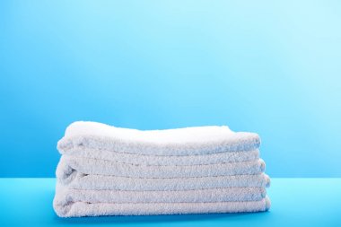 一堆干净柔软的白色毛巾在蓝色背景 一堆干净柔软的白色毛巾在蓝色背景