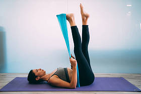 年轻运动的有吸引力的妇女实践普拉提与抵抗带在白色都市演播室。瑜伽和普拉提生活方式健康理念