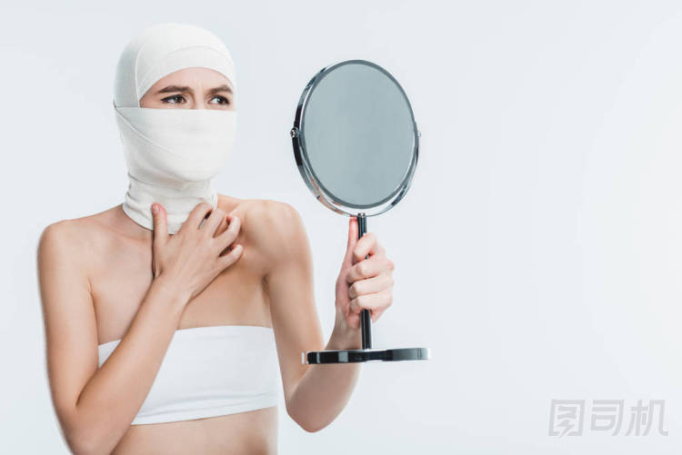 害怕的婦女整形手術(shù)后的臉上看著鏡子孤立在白色