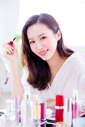 美丽的女人使用睫毛膏刷和微笑给你在家